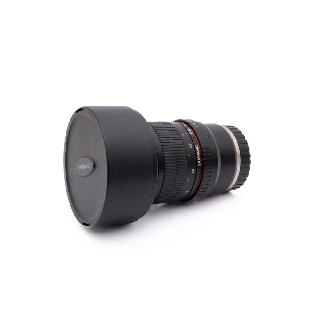 Samyang 14mm f2.8 SonyE-1 Fujinon XF 50-140mm f/2.8 OIS WR - Käytetty objektiivi, johon on kiinnitetty vastavalosuoja, makaa kyljellään valkoista taustaa vasten, ja siinä on useita säätörenkaita ja punaisia korostusviivoja.