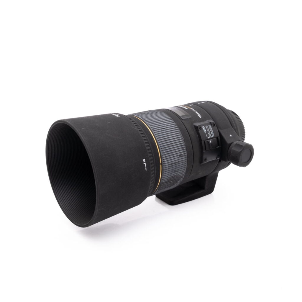 Sigma 150mm f-2.8 macro NikonF-1 Nikon AF-S Nikkor 50mm f/1.8 G (Kunto K4.5) - Käytetty objektiivi vastavalosuojalla, jossa on säätörenkaat ja kytkimet ja joka on esitetty valkoisella taustalla.