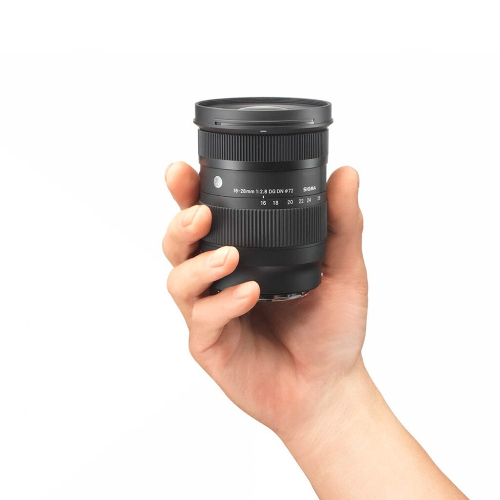 Sigma-16-28mm-f2.8-DG-DN-C-3 Hand holding the Sigma 16-28mm f/2.8 DG DN Contemporary lens for Sony E against a white background.