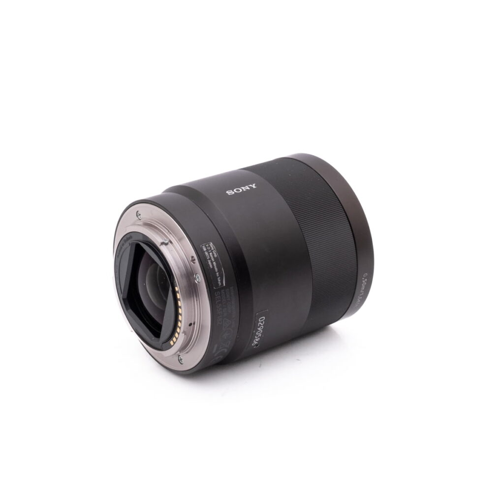 Sony 55mm f1.8 0586-3 Fujinon XF 50-140mm f/2.8 OIS WR - Käytetty -objektiivi makaa kyljellään valkoista taustaa vasten, ja siinä näkyy metallinen kiinnitys elektronisilla koskettimilla ja kuvioitu musta piippu.