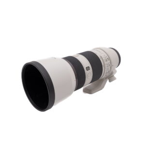 Fujinon XF 50-140mm f/2.8 OIS WR - Käytetty on suuri valkoinen teleobjektiivi, jossa on musta kahva, kiinnitysteline ja useita säätörenkaita ja kytkimiä, kuvassa valkoista taustaa vasten.
