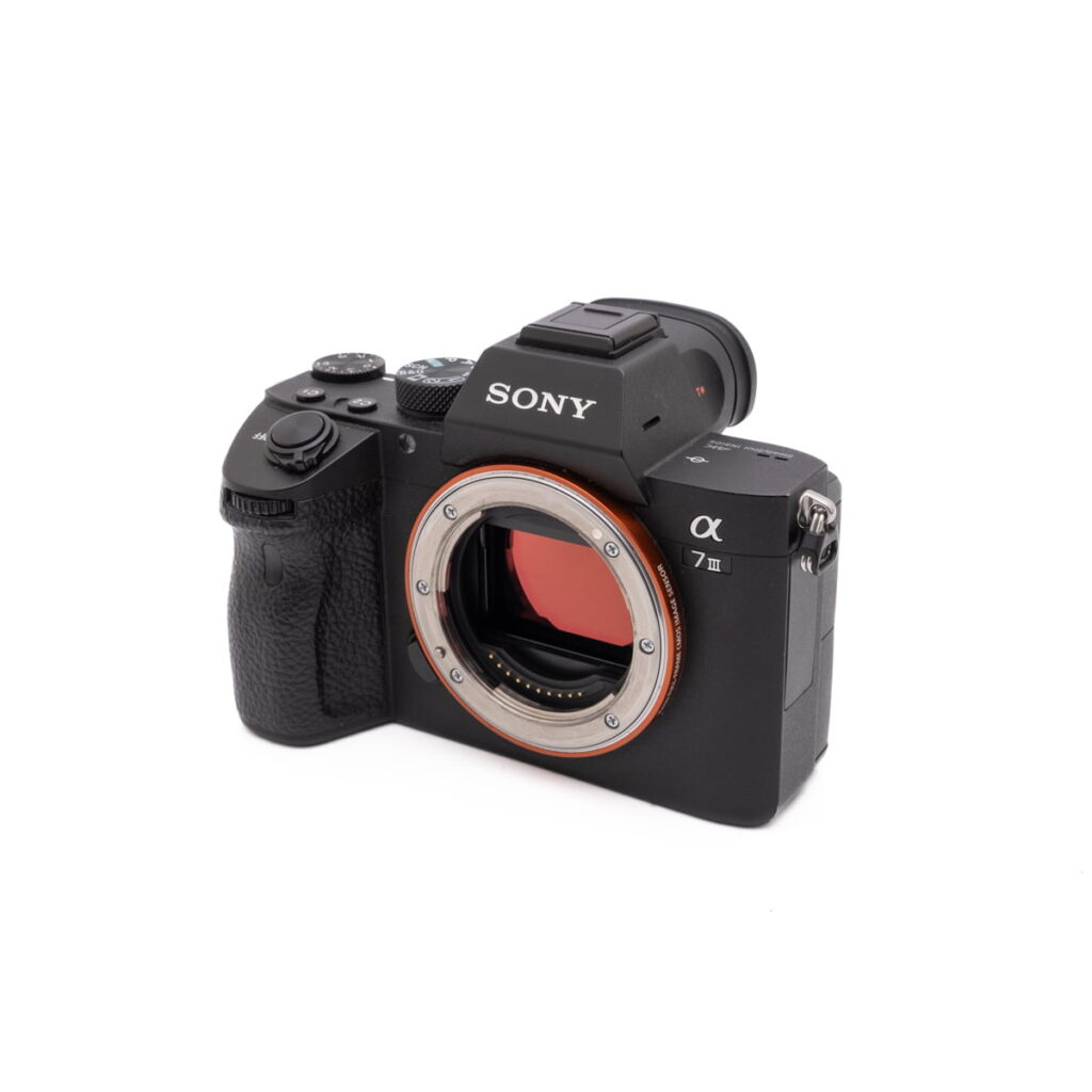 Sony-A7III-121-2 Sony A7 III - Käytetty peilitön kamerarunko ilman objektiivia kuvattuna kuvakulmasta, jossa näkyy kenno ja säätimet.