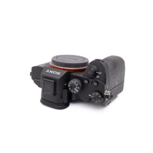 Sony-A7III-121-4 Musta Sony A7 III - Käytetty -kameran runko näkyy ylhäältä alaspäin suunnattuna, ja sen säätimet, painikkeet ja kuvioitu kahva korostuvat. Objektiivia ei ole kiinnitetty.
