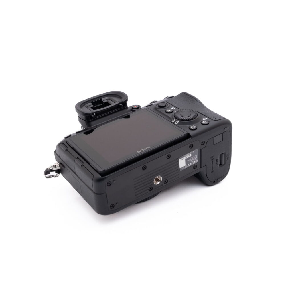Sony-A7III-274-5 Sony A7 III (SC 2800, Kunto K5) - Käytetty on musta digitaalikamera, jossa on suuri kallistettava näyttö, useita ohjauspainikkeita ja etsin, kuvattuna takaa ja hieman ylhäältä valkoisella pohjalla.