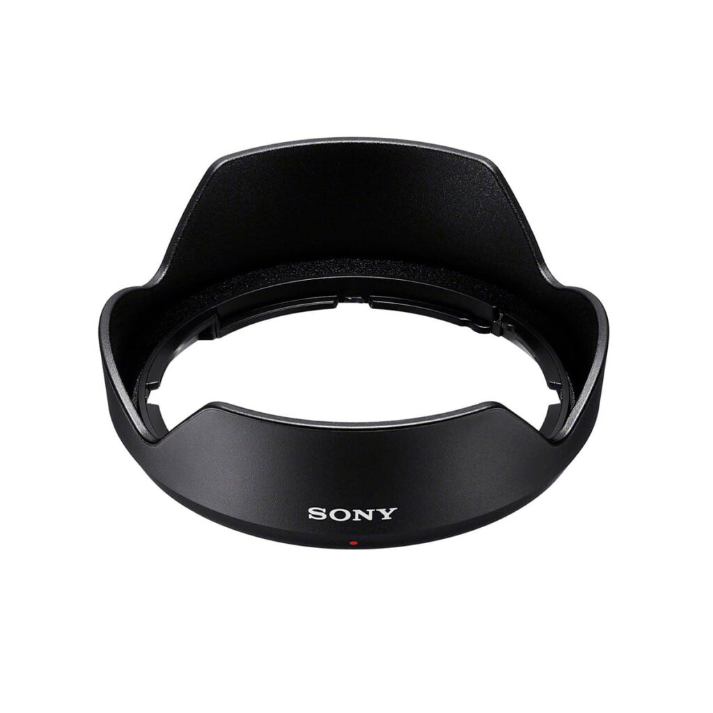 Sony-E-11mm-f1.8-5 Sony E 11mm f/1.8 -objektiivin musta vastavalosuoja näkyy valkoisella pohjalla, ja siinä on terälehden muotoinen kuvio, valkoisella painettu "SONY" etupuolella ja pieni punainen piste logon alapuolella.