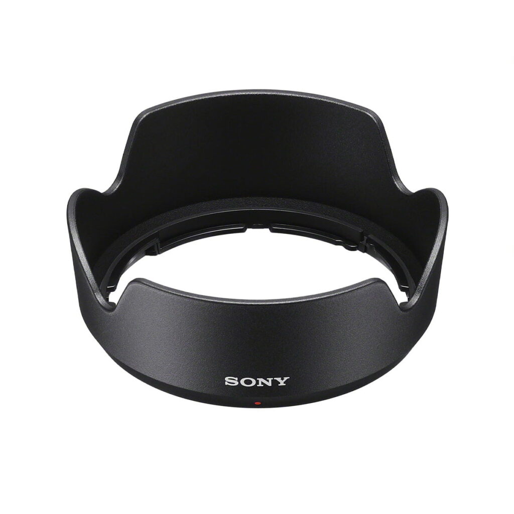 Musta vastavalosuoja Sony E 15mm f/1.4 G -objektiiville, jossa on terälehden muotoinen muotoilu, jossa on Sony-logo ja punainen piste edessä, kuvattuna valkoista taustaa vasten.