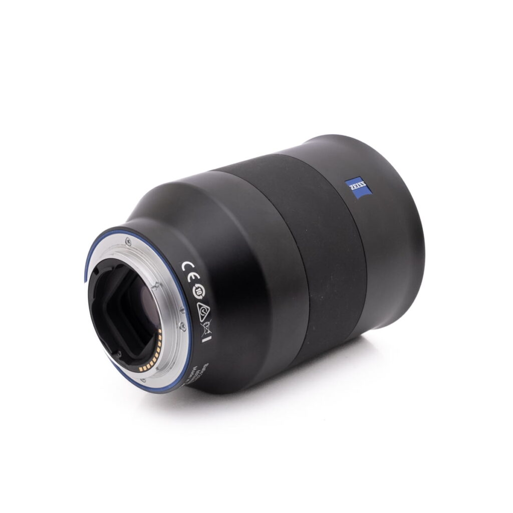 ZeissBatis 135mm f2.8 SonyE-3 Nikon Nikkor Z DX 16-50mm f/3.5-6.3 VR - Käytetty -objektiivi makaa kyljellään, ja siinä näkyy metallinen kiinnitys, elektroniset koskettimet ja sertifiointisymbolit valkoista taustaa vasten.