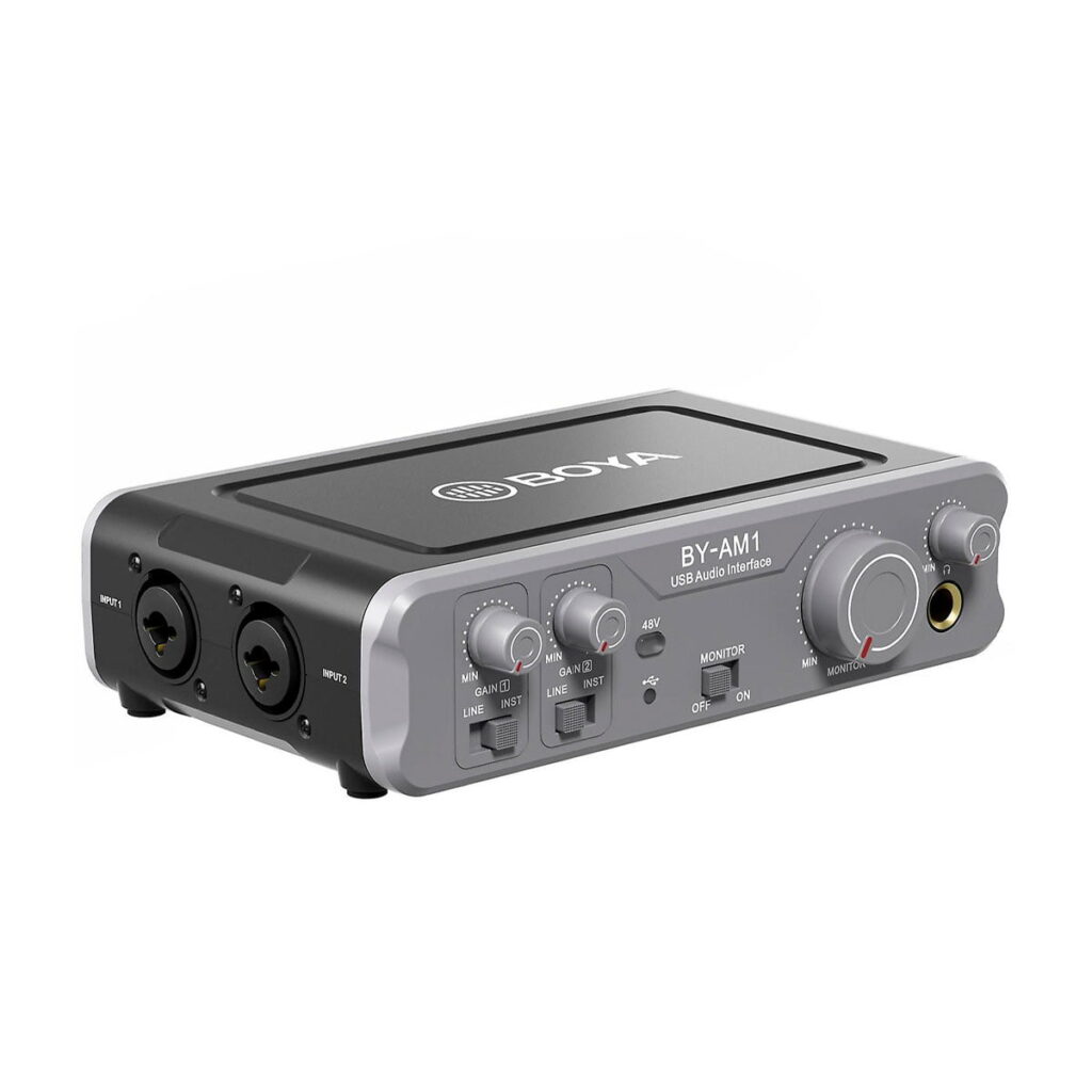 Boya-BY-AM1 Boya BY-AM1 2-kanavainen XLR mikseri on harmaa USB-ääniliitäntä, jossa on useita tulo-/lähtöportteja, säätönupit ja kytkimet etupuolella, ja jonka yläosassa on BOYA-logo ammattimaiseen äänentallennukseen ja monitorointiin.