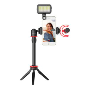 Boya-BY-VG350-2 Henkilö hymyilee selfieä varten älypuhelimellaan, joka on kiinnitetty Boya BY-VG350 Video-Kit -laitteeseen, jossa on LED-valo ja mikrofoni - ihanteellinen asetelma vloggausta tai sisällön luomista varten.