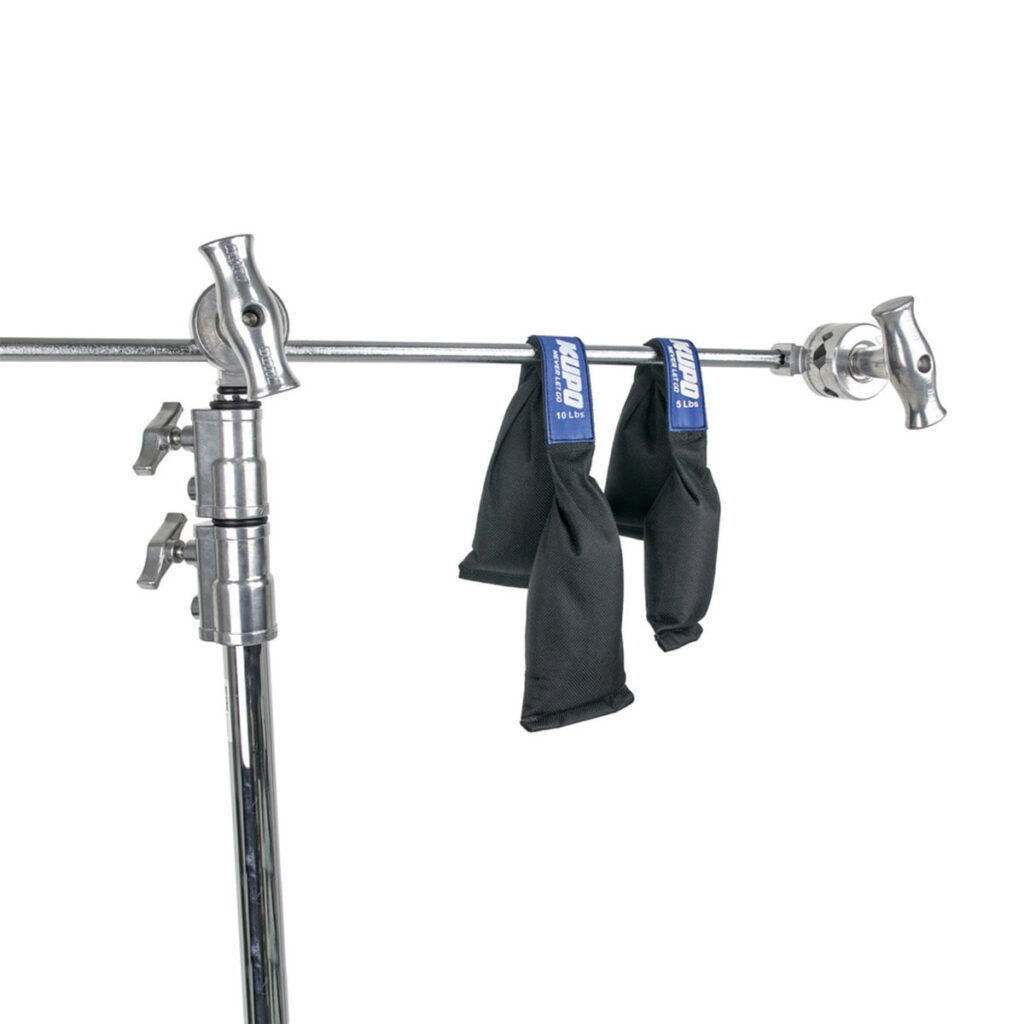 Kupo-KSW-05-2 Metallinen C-teline, jonka vaakavarressa roikkuu kaksi Kupo KSF-15 Shot Bag -laukkua (6,9 kg kumpikin), joita käytetään yleisesti elokuvissa ja valokuvauksessa valaisulaitteiden vakauttamiseen.