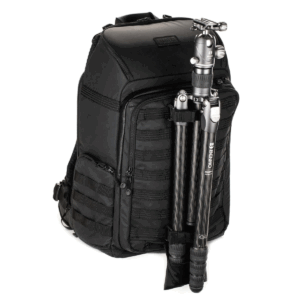 Tenba-Axis-V2-32L-7 The Tenba Axis V2 32L Backpack is a black camera backpack with multiple compartments and zippers and a carbon fiber tripod that is securely attached to the front.