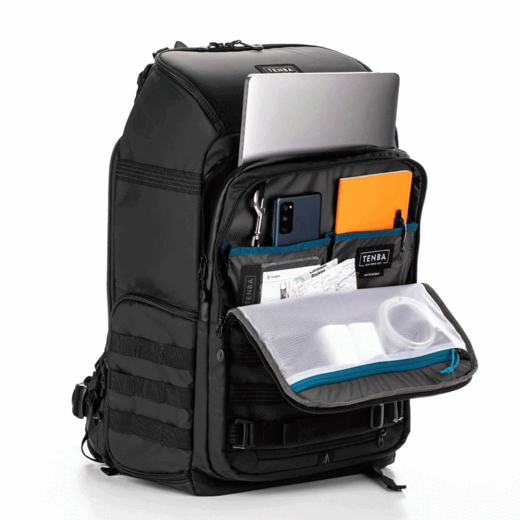 Tenba-Axis-V2-32L-9 The Tenba Axis V2 32L Backpack is pictured in black with the front compartment open and several pockets to neatly hold a laptop, tablet, smartphone, orange notebook, pens, papers, charging cable and accessories.