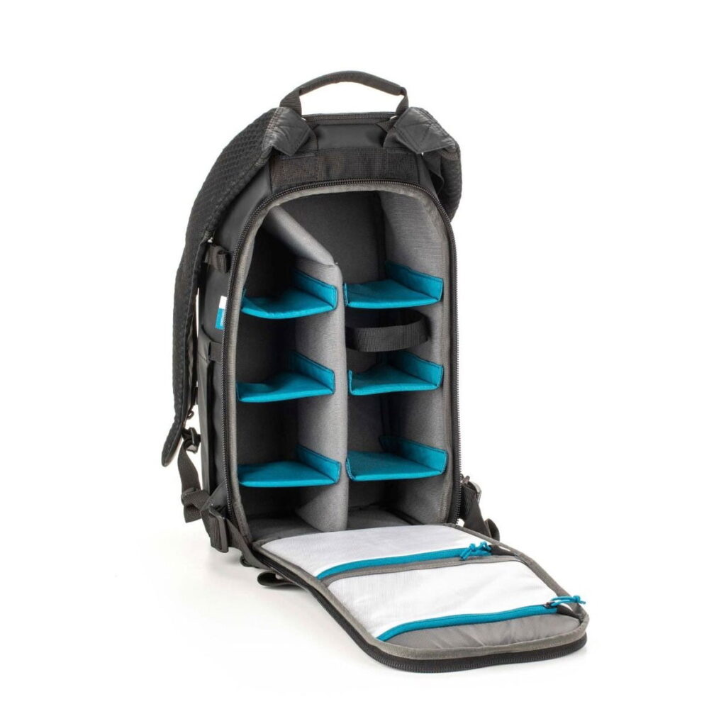 Tenba-axis V2-16L-3 The Tenba Axis V2 16L backpack is shown open to reveal several padded, adjustable compartments with blue dividers for organizing gear and two zippered mesh pockets inside the front flap.
