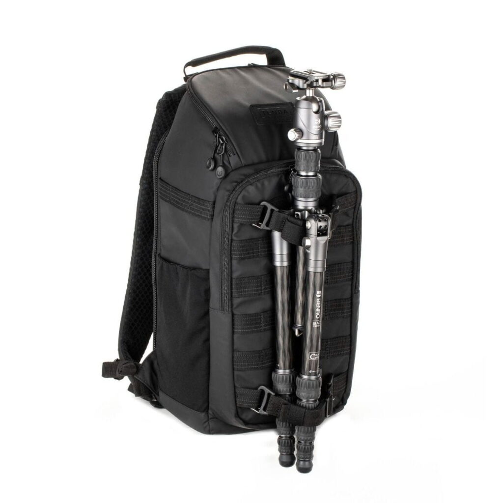 Tenba-axis V2-16L-5 The Tenba Axis V2 16L Backpack is a black camera backpack with multiple zippered compartments, a top handle and a silver stand that is attached vertically to the front.