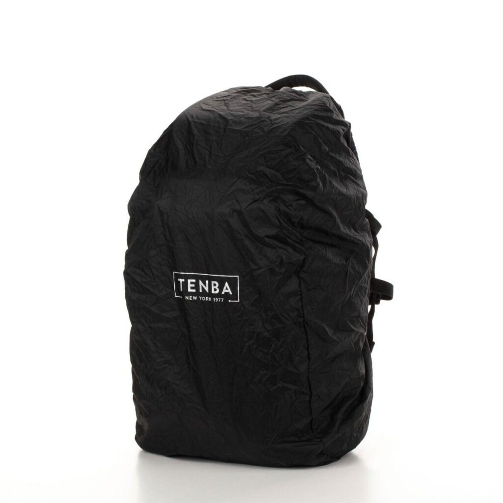 Tenba-axis V2-16L-7 The Tenba Axis V2 16L camera backpack, in black with rain cover, displays the white Tenba logo and the text "New York 1977" on the front against a white background.