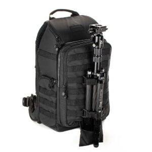 Tenba-axis-V2-20L-2 Pystyssä seisovassa Tenba Axis V2 20L -reppu -kamerareppu -kamerareppu sisältää useita vetoketjullisia lokeroita ja mustan jalustan, joka on kiinnitetty sivuun säädettävillä hihnoilla ja pienellä taskulla.