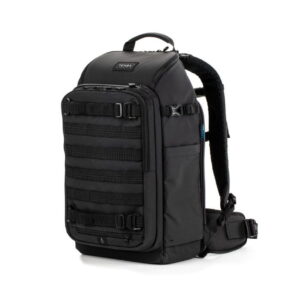 Tenba-axis-V2-20L Tenba Axis V2 20L Backpack -kamerareppu on musta taktisen tyylin reppu, jossa on useita etuhihnoja, sivutaskut ja pehmustetut olkahihnat, jotka näkyvät pystyasennossa valkoisella pohjalla.