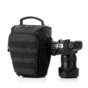 Tenba-axis V2-4L-4 The Tenba Axis V2 4L Top Loader camera bag with handle sits next to a professional DSLR camera with a large lens and lens cover, both against a white background.