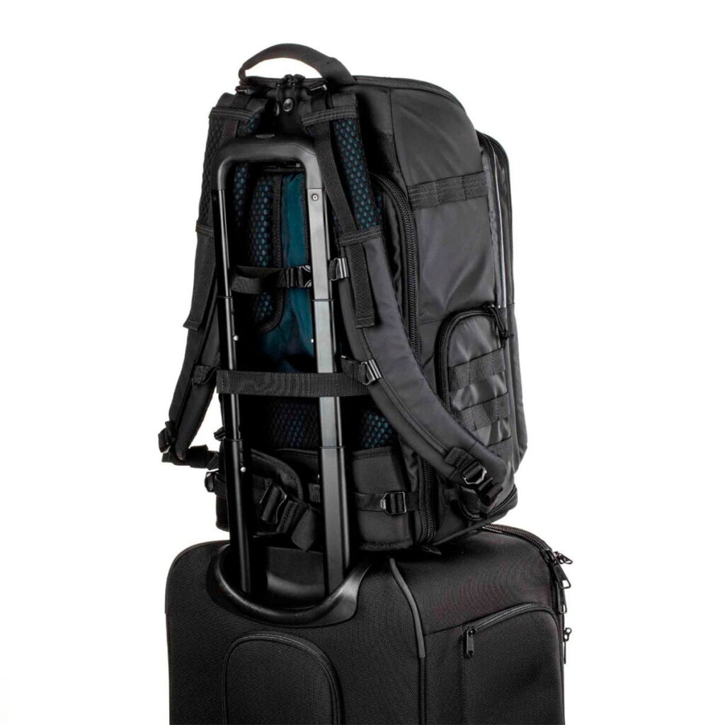 Tenta-axis V2-5 The Tenba Axis V2 24L camera backpack is securely attached to the telescopic handle of the black roller bag, showing how it can be carried conveniently on top of your luggage for easy transport.