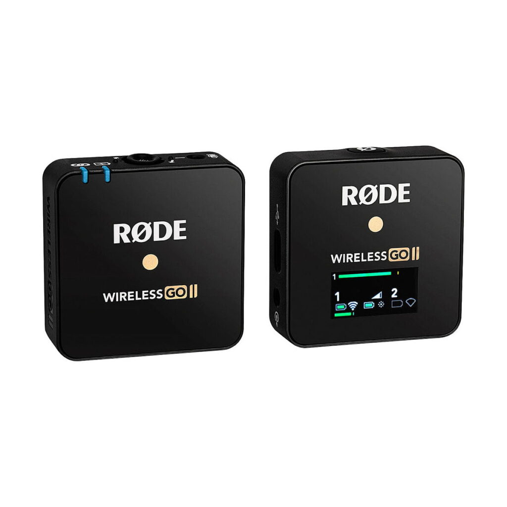 Rode_Wireless_GO_II_single_001 Kaksi mustaa, neliönmuotoista Rode Wireless Go II Single Set -langaton mikrofonijärjestelmä -lähetintä näytetään vierekkäin; oikeanpuoleisessa laitteessa on näyttö, jossa on akku- ja liitäntäkuvakkeet, kun taas vasemmanpuoleisessa näkyy vain logo.
