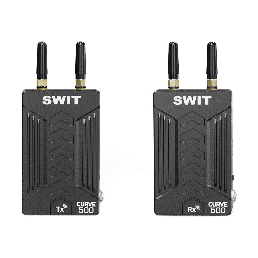 Swit_Curve500_Tx_Rx_Wireless_Kit_001 Kaksi mustaa Swit Curve500 Tx+Rx Wireless Kit -lähetintä antenneineen on vierekkäin. Vasemmanpuoleisessa yksikössä on merkintä Tx ja oikeanpuoleisessa Rx; molemmissa lukee "CURVE 500" ja niiden etupuolella on Chevron-kuvio.
