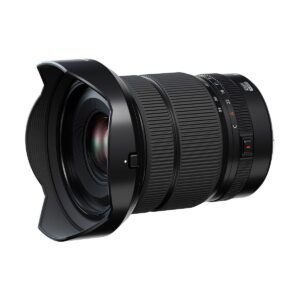 Fujifilm Fujinon GF 20-35mm f/4 R WR -objektiivissa on suuri etulasi, kuvioidut zoomaus- ja tarkennusrenkaat, sivusäätökytkimet, terälehden muotoinen huppu, ja se on mustaa, kuvassa hieman vinossa.
