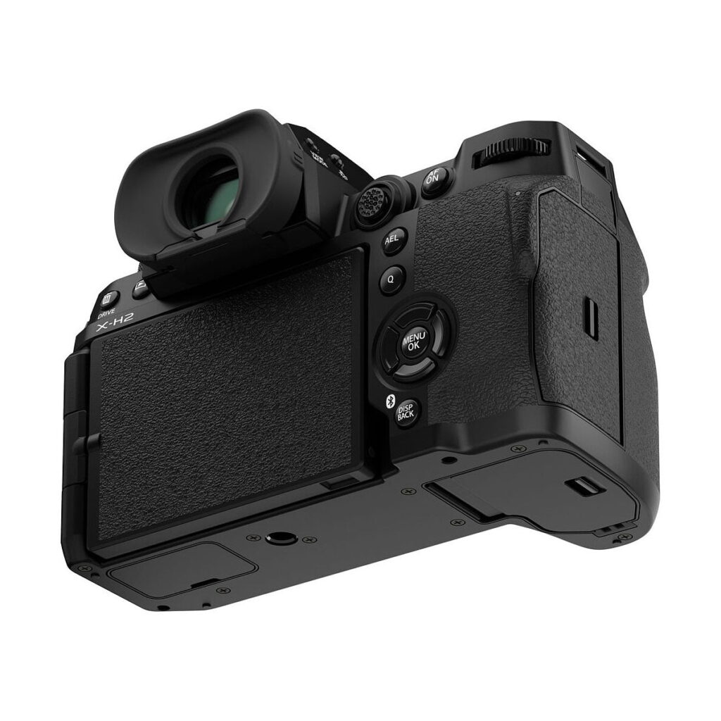 Fujifilm_X-H2_006 Fujifilm X-H2 -järjestelmäkamerassa on suuri nestekidenäyttö, useita säätimiä ja elektroninen etsin takaa ja hieman alhaalta katsottuna, jossa korostuvat yksityiskohtaiset painikkeet ja kuvioitu kahva.