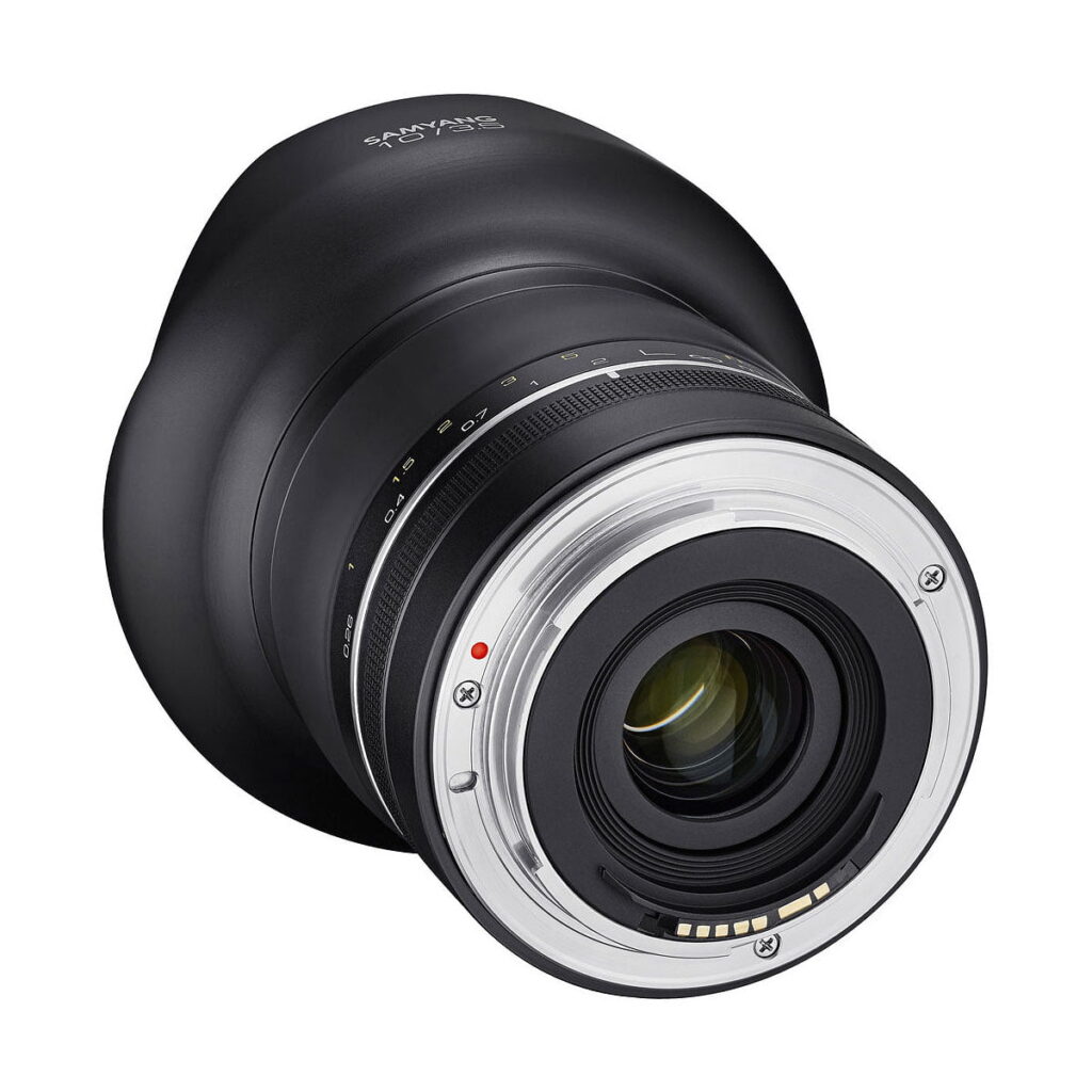 Samyang_10mm_f_3_5_XP_003 Lähikuvassa Samyang XP 10mm f/3.5 - Canon EF -objektiivista näkyy takaosan metallinen kiinnitys, elektroniset koskettimet ja "Samyang"-brändi mustassa tynnyrissä.