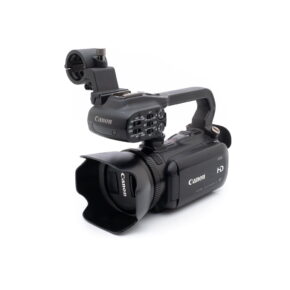 Canon XA10 (sis.ALV24%) - Käytetty HD-videokamera mustana, jossa on suuri linssinsuojus, ulkoinen mikrofonikiinnitys ja useita ohjauspainikkeita valkoisella pohjalla.
