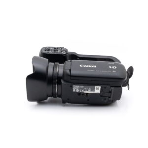 canon_xa10-3 Käytetty Canon XA10 (sis.ALV24%) -videokamera on kuvattu kyljellään valkoista taustaa vasten, jolloin objektiivi, ohjauspainikkeet, tuotemerkki ja tulo-/lähtöportit tulevat esiin.