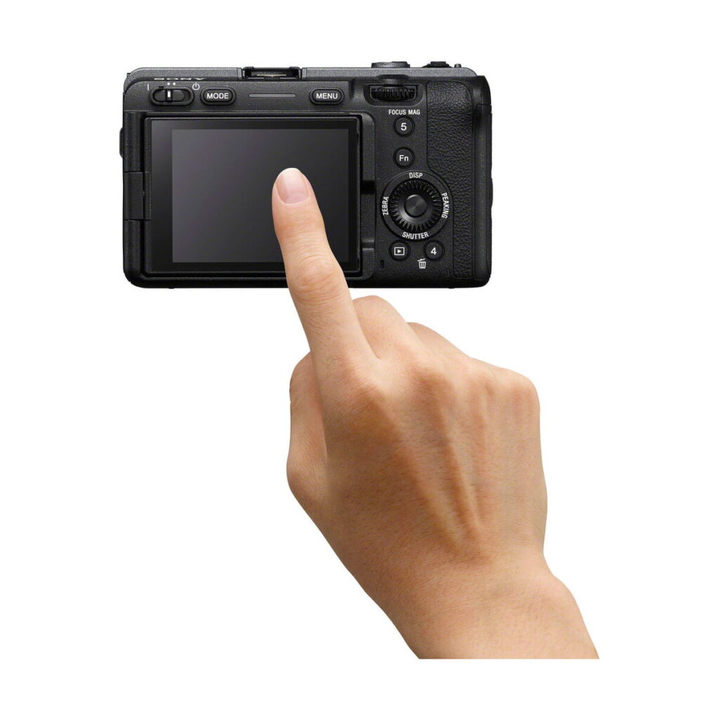 Käsi, jonka etusormi on ojennettu, koskettaa Sony FX30 -videokameran takana olevaa LCD-näyttöä valkoista taustaa vasten.