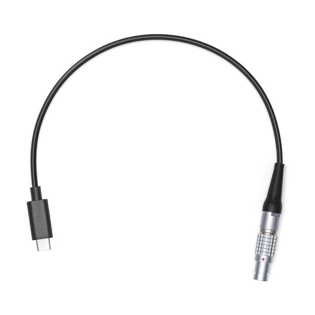 DJi_Transmission_Combo_013 DJI Transmission Combo musta kaapeli, jonka toisessa päässä on USB-C-liitin ja toisessa päässä hopeinen metallinen lukitusliitin, kuvassa valkoista taustaa vasten.