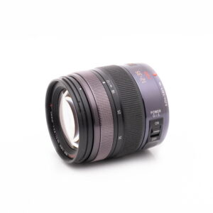 Lumix Vario 12-35-2 Musta Panasonic Lumix Vario 12-35mm f/2.8 Power O.I.S - Käytetty -objektiivi näkyy valkoisella pohjalla vasemmalle suunnattuna, ja siinä näkyvät tarkennus- ja zoomausrenkaat sekä Power O.I.S. -kytkin.