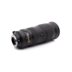 Nikkor 200-500mm-3 Nikon AF-S Nikkor 200-500mm f/5.6E ED VR - Käytetty teleobjektiivi, jossa on kultaiset ja valkoiset merkinnät, on kuvattu kulmassa valkoisella taustalla, ja siinä näkyy objektiivin kiinnitys ja näkyvät tuotemerkin merkinnät.