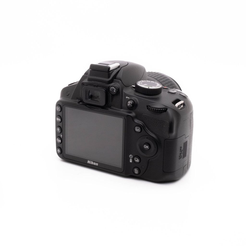 Nikon D3200 kit-2 Musta Nikon D3200 + 18-55mm (SC 3378) - Käytetty DSLR-kamera on kuvattu takavasemmalta, ja sen nestekidenäyttö, ohjauspainikkeet ja etsin näkyvät valkoista taustaa vasten.