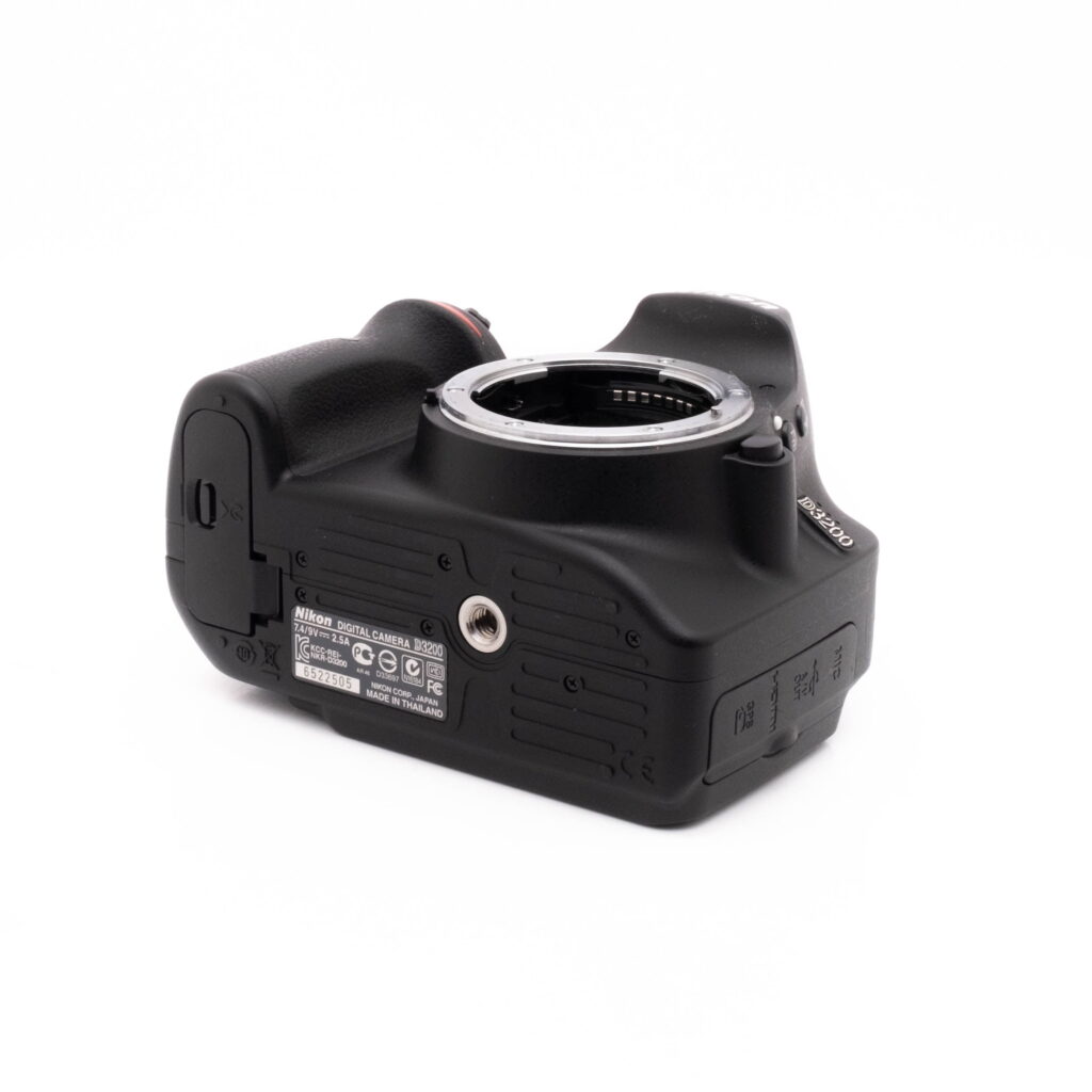 Nikon D3200 kit-4 Nikon D3200 + 18-55mm (SC 3378) - Käytetty kamera näkyy matalasta kulmasta, jolloin pohja, kahva ja objektiivin kiinnitys korostuvat valkoista taustaa vasten.