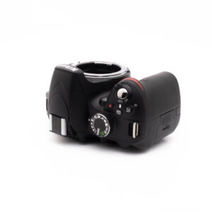 Nikon D3200 kit-5 Nikon D3200 + 18-55mm (SC 3378) - Käytetty näytetään ylhäältäpäin valkoisella pohjalla, jossa näkyvät sen painikkeet, säätimet ja objektiivin kiinnitys ilman kiinnitettyä objektiivia.