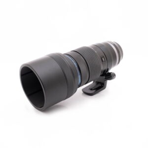Canon EF 100-400mm f/4.5-5.6 L IS II USM -teleobjektiivi (käytetty), jossa on jalustakiinnitysrengas, suuri ja musta, on suunnattu hieman vasemmalle valkoisella taustalla.