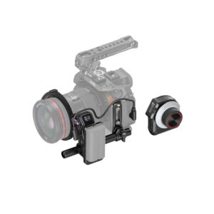 SmallRig_MagicFIZ_Wireless_Follow_Focus_Basic_Kit_3781_001 SmallRig 3781 Magic FIZ Wireless Follow Focus Basic Kit on kuvassa kiinnitettynä kamerarigiin, ja sen ohjauspyörä ja moottoriyksikkö on korostettu, kun taas kamera ja rig on osittain häivytetty.