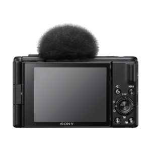 Sony_ZV-1F_002 Kuvassa näkyy takana musta Sony ZV-1F -kompaktikamera, jossa on suuri LCD-näyttö ja ohjauspainikkeet, sekä sumea mikrofoni tuulisuoja kiinnitetty yläosaan.