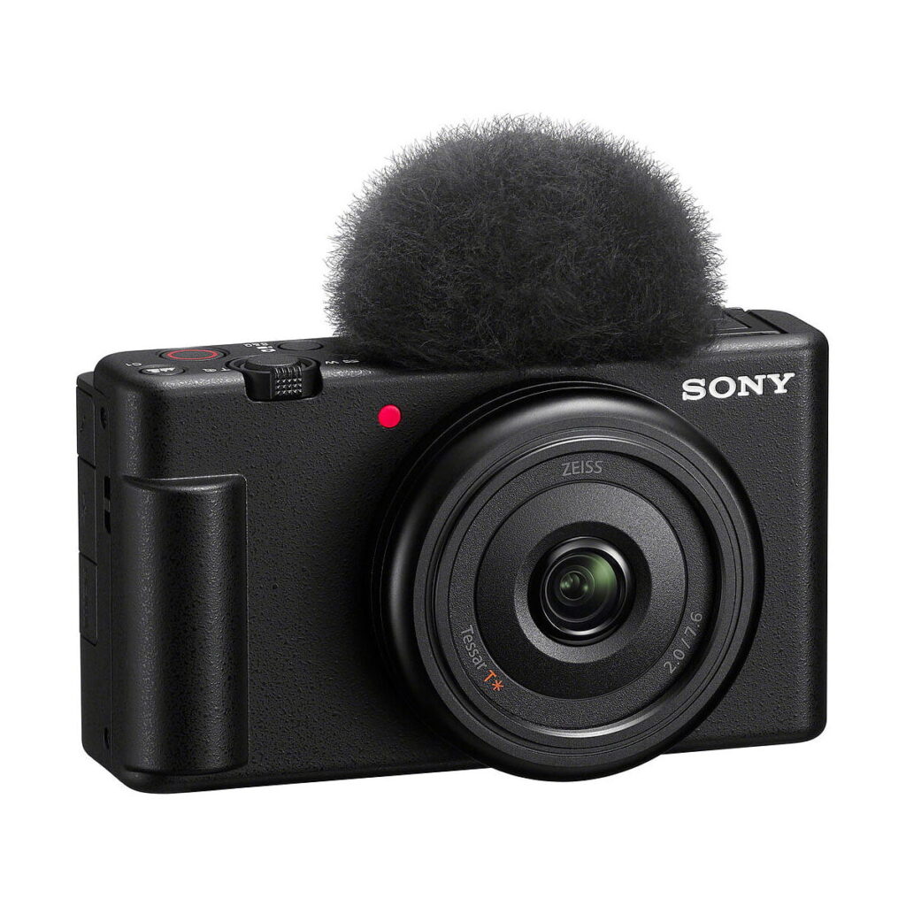 Sony_ZV-1F_003 Sony ZV-1F -kompaktikamera on kompakti musta digitaalikamera, jossa on Zeiss-merkitty objektiivi, ohjauspainikkeet ylä- ja takapuolella sekä irrotettava mikrofonin tuulisuoja ("kuollut kissa").