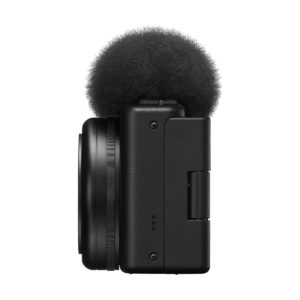 Sony_ZV-1F_006 Sivukuva Sony ZV-1F -kompaktikamerasta, kompaktista mustasta digitaalikamerasta, jossa on objektiivi ja sumea tuulisuoja äänen kohinan vähentämiseksi, eristettynä valkoiselta taustalta.