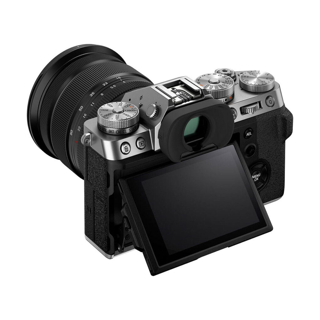 Fujifilm X-T5 + XF 16-80mm f/4 R OIS WR, hopea, näytetään takaa hopeanvärisellä ja mustalla rungolla, ulospäin kallistettavalla LCD-näytöllä sekä näkyvillä olevilla valintakiekoilla, painikkeilla ja etsimellä takana ja ylhäällä.