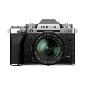 Fuji_X-T5-18-55mm_Hopea_001 Fujifilm X-T5 + XF 18-55mm f/2.8-4 R LM OIS - Hopea-kamera, jossa on hopeanvärinen ja musta runko ja kiinnitetty zoom-objektiivi, etupuolella valkoisella taustalla.