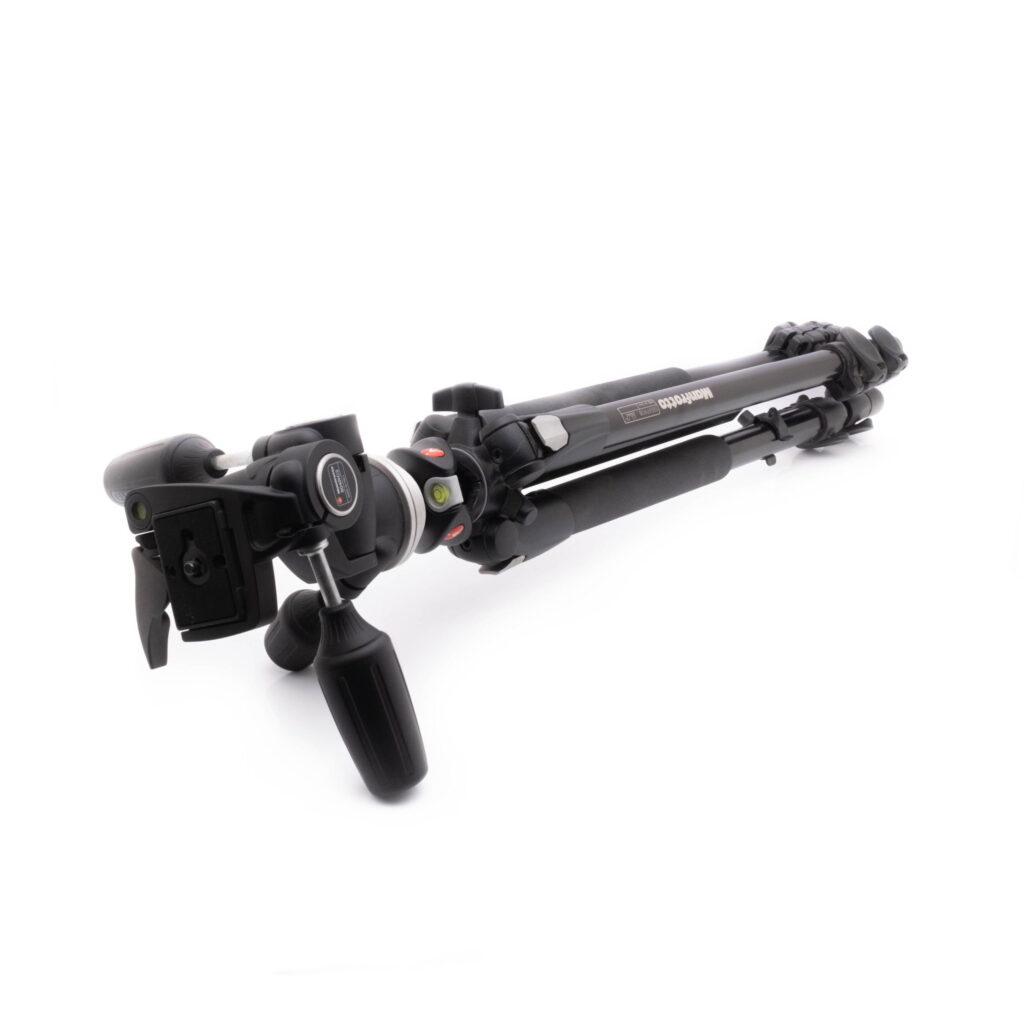 Manfrotto 90-1 Käytetty Manfrotto 190XPROB kolmijalkainen jalusta 804RC2 3-suuntainen pää, musta, jossa on säädettävät jalat ja joka on kuvassa taitettuna valkoisella pinnalla.