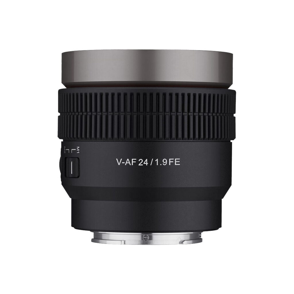 Samyang_V-AF_24mm_T1_9-Sony_FE_001 Musta Samyang V-AF 24mm T1.9 -objektiivi Sony FE:hen, jossa on kuvioitu tarkennusrengas ja metallinen kiinnitys, on esillä valkoista taustaa vasten.