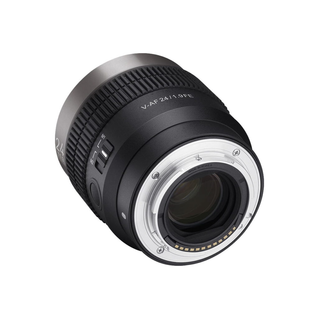 Samyang_V-AF_24mm_T1_9-Sony_FE_005 Mustaa Samyang V-AF 24mm T1.9 - Sony FE -objektiivia käännetään niin, että sen elektroniset koskettimet, metallinen kiinnitys, sivukytkimet ja tynnyrissä olevat merkinnät "V-AF 24/1.8 FE" ja "24" näkyvät.