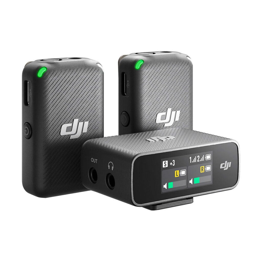DJi_Mic_001 DJI Mic Dual Kit -langaton mikrofonijärjestelmä sisältää kaksi mustaa lähetintä, joissa on vihreät LEDit, sekä vastaanottimen, jossa on näyttö ja useita ääniportteja.