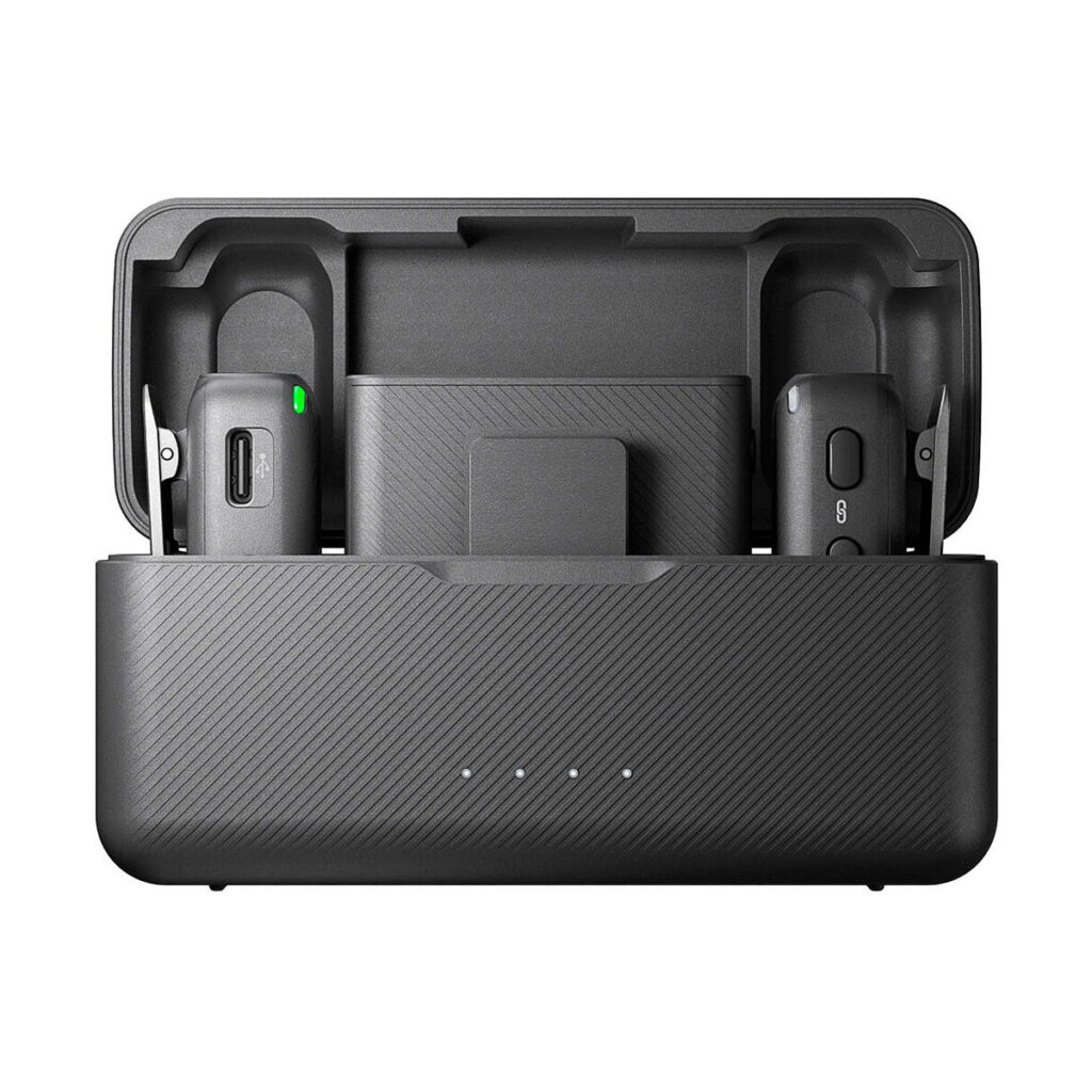 DJi_Mic_002 DJI Mic Dual Kit -langaton mikrofonijärjestelmä on musta latauskotelo, jossa on avoin kansi ja jonka sisällä on kaksi langatonta mikrofonilähetintä ja vastaanotin. Kotelon etupuolella näkyy neljä merkkivaloa.