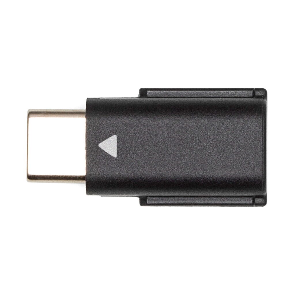DJi_Mic_008 A DJI Mic Dual Kit -langaton mikrofonijärjestelmä USB-C adapteri, musta, jossa pieni valkoinen nuoli rungossa, esillä valkoisella taustalla.